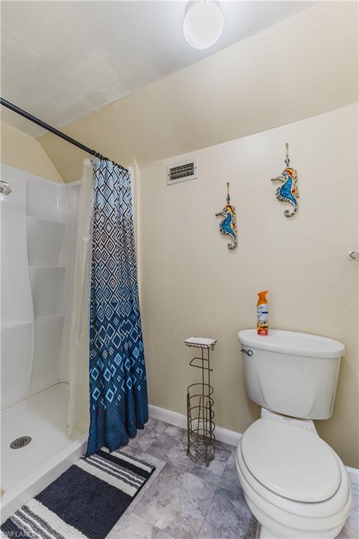 Full bath featuring a shower stall and baseboards