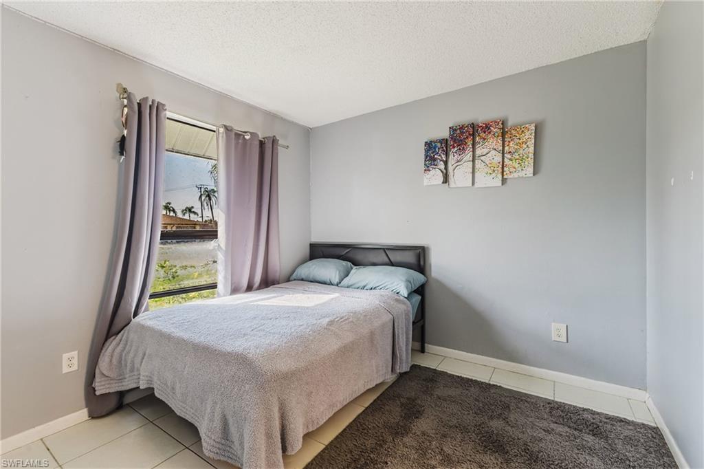 Tiled bedroom with a textured ceiling and baseboards
