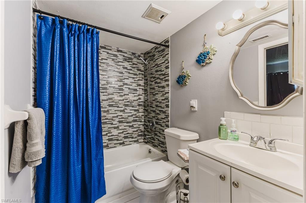 Bathroom with shower / bath combination with curtain and vanity