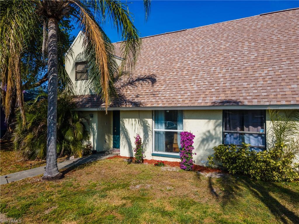 View of front of house with a shingled roof, stucco siding, and a front lawn