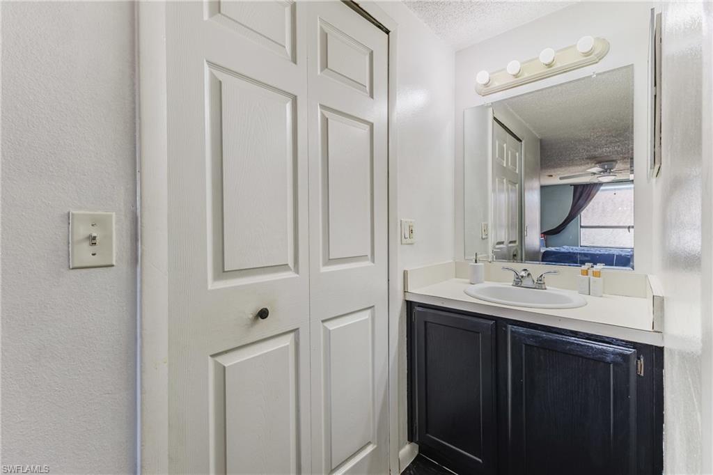 Bathroom featuring vanity, a textured ceiling, a closet, connected bathroom, and ceiling fan