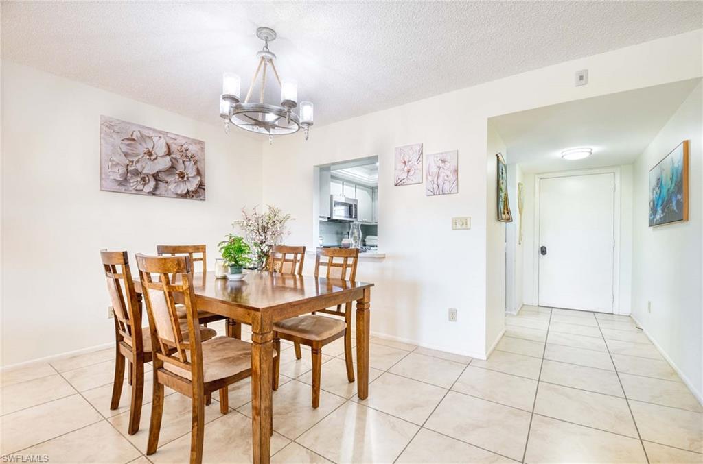 Dining room with a chandelier, a textured ceiling, and light tile patterned flooring