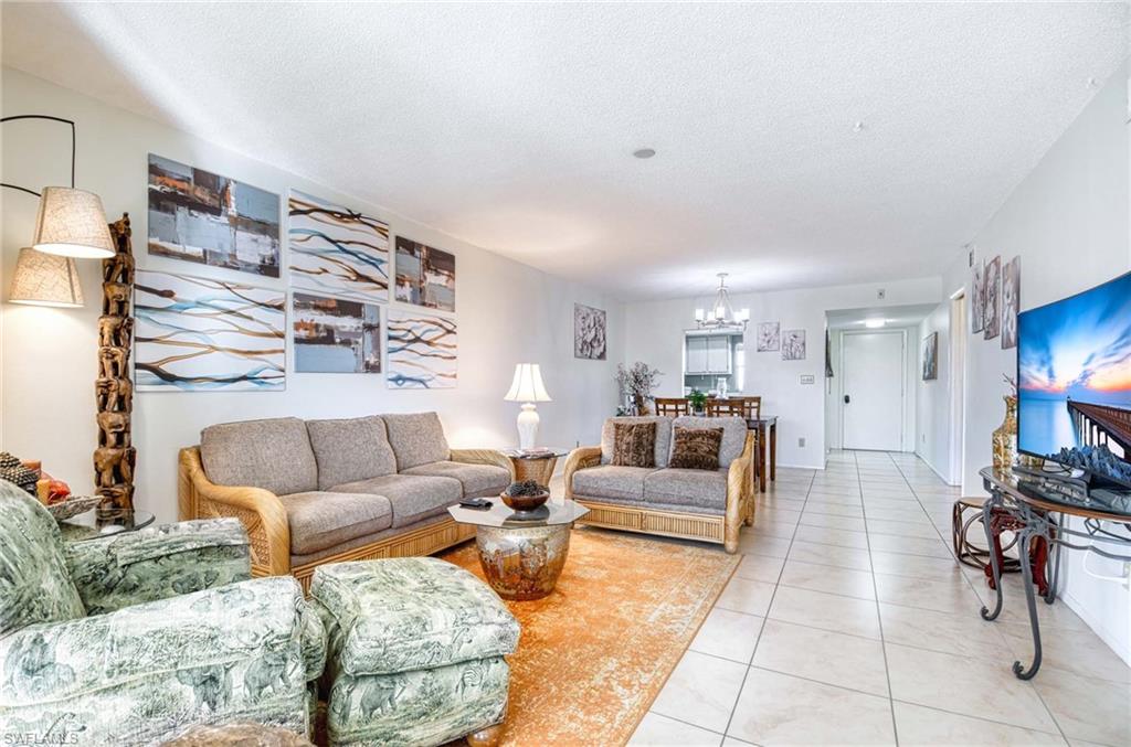 Living room featuring a chandelier, tile patterned floors, and a textured ceiling