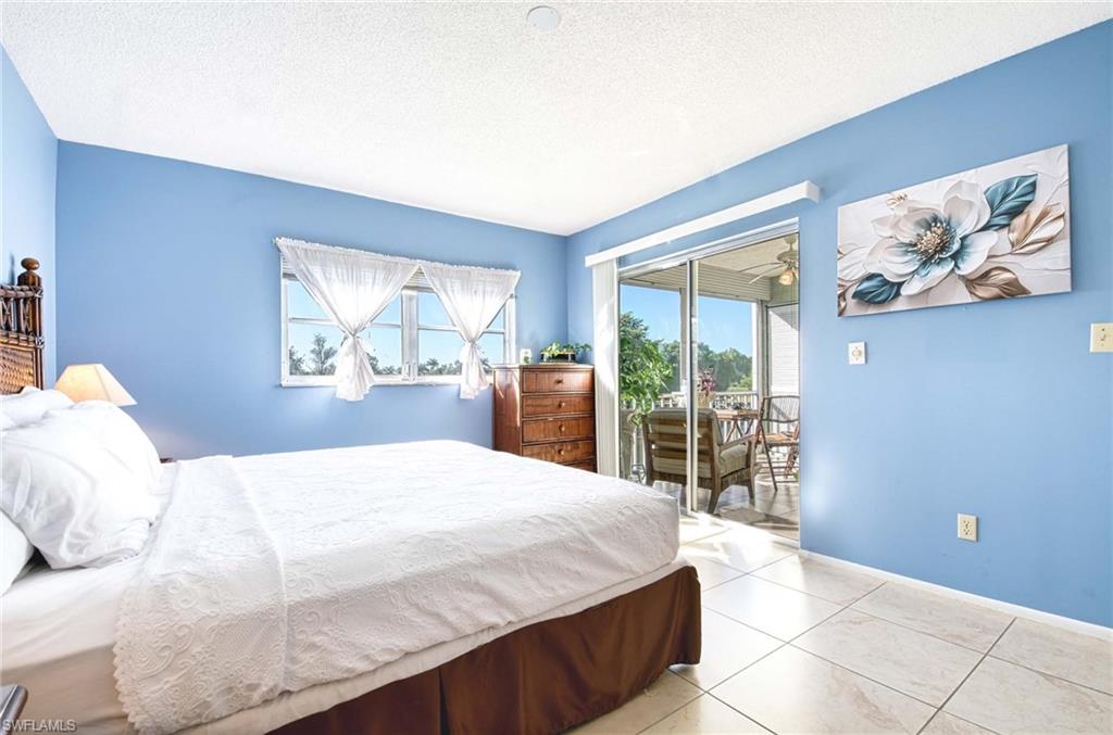Bedroom featuring multiple windows, a textured ceiling, access to outside, and light tile patterned floors
