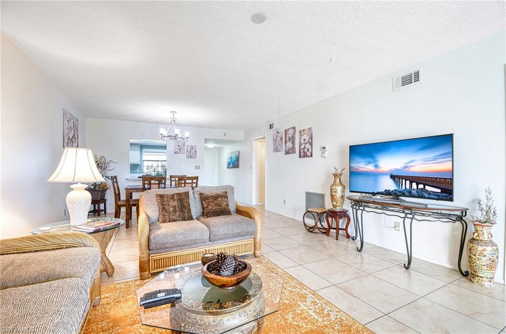 Living room featuring light tile patterned flooring, a textured ceiling, and a chandelier