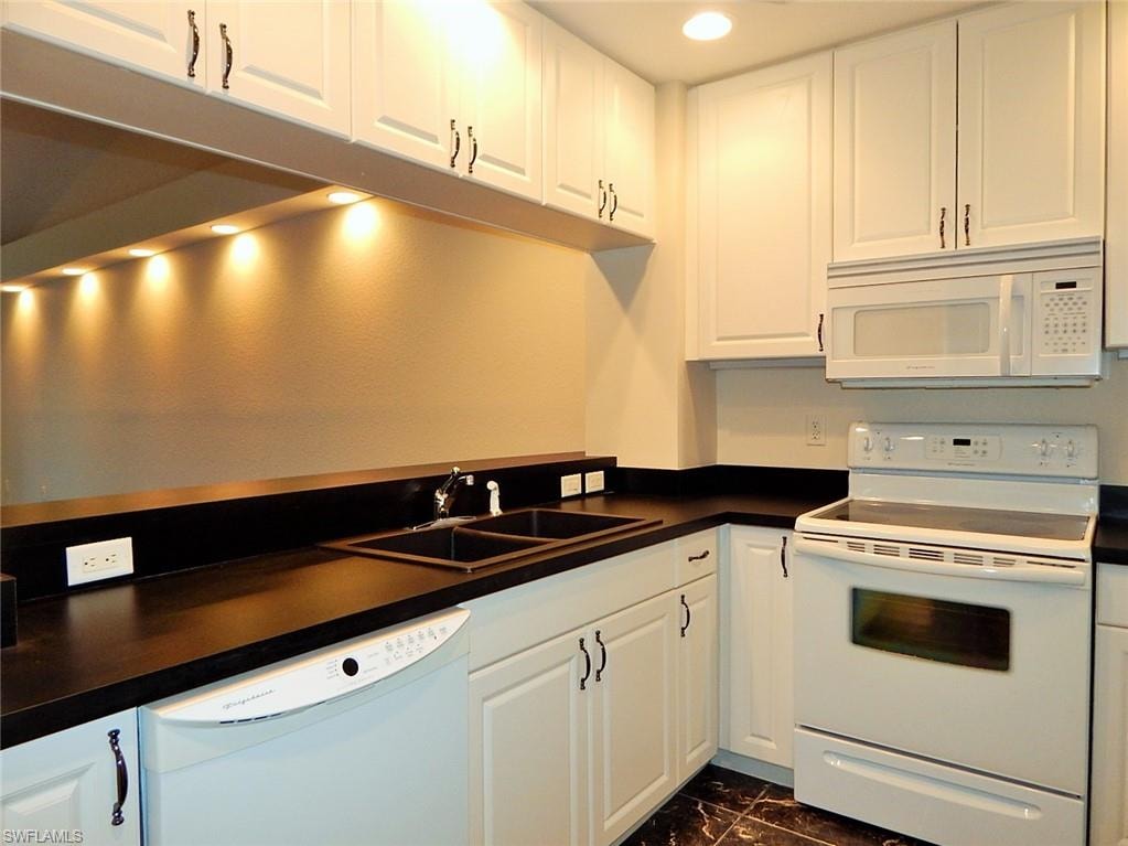 Kitchen with white appliances, dark countertops, white cabinets, recessed lighting, and dark marble finish floors