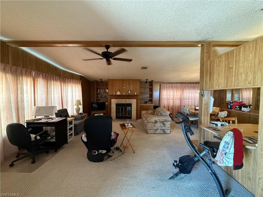 Office featuring a textured ceiling, carpet flooring, a glass covered fireplace, healthy amount of natural light, and built in features
