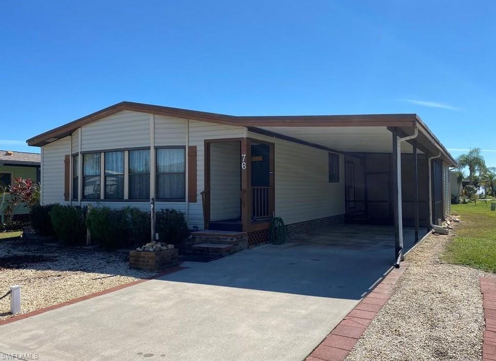 Manufactured / mobile home with concrete driveway, a sunroom, and a carport