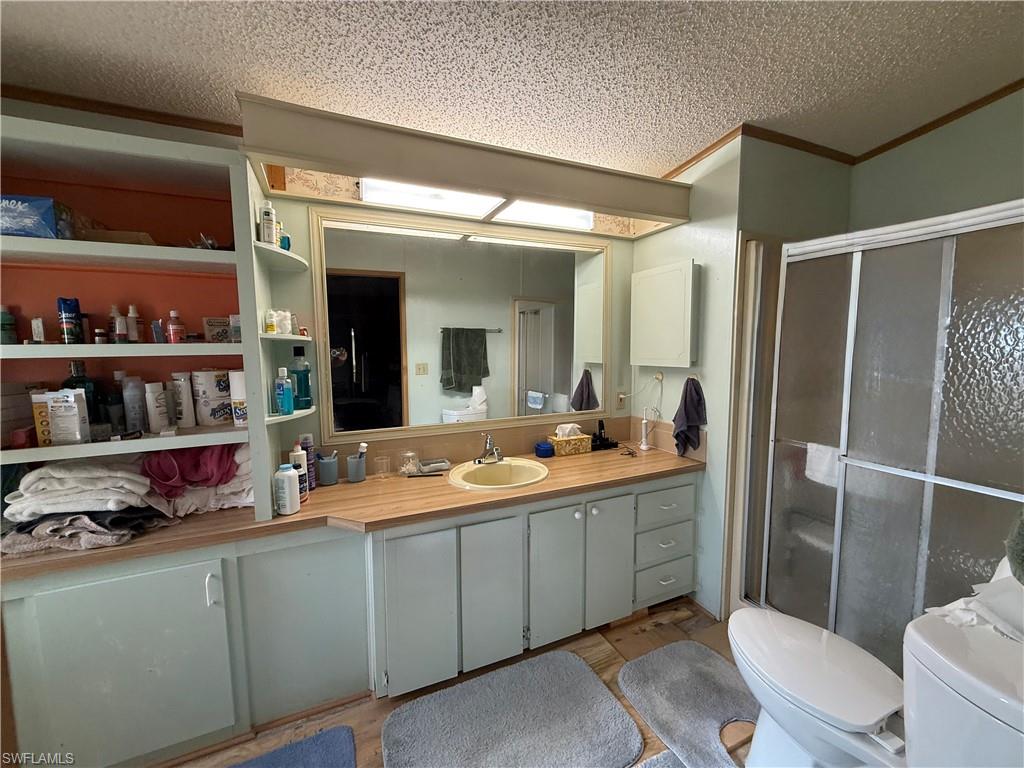 Bathroom with a stall shower, vanity, and a textured ceiling
