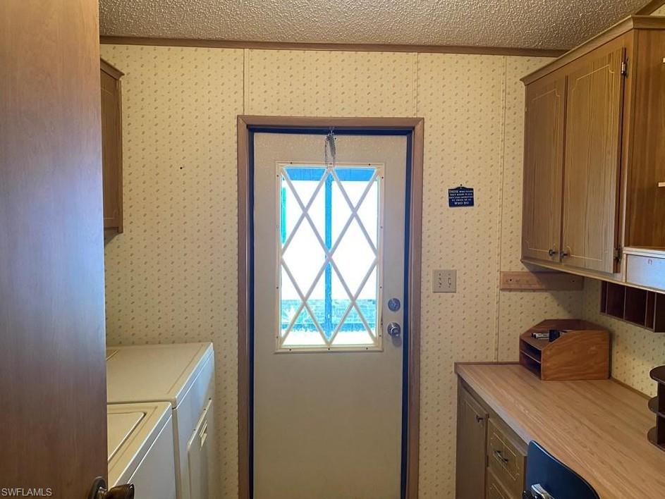 Laundry room with cabinet space, separate washer and dryer, and a textured ceiling
