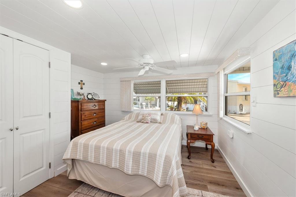 Bedroom with wood walls, recessed lighting, a closet, wood finished floors, and ceiling fan