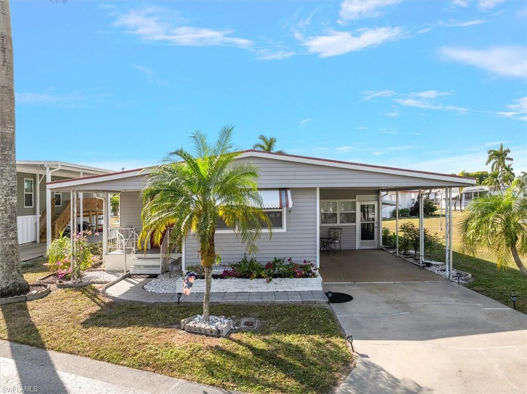 Manufactured / mobile home with concrete driveway, an attached carport, and a front lawn
