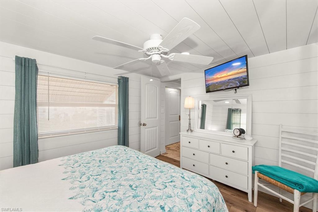 Bedroom with wood walls, wood finished floors, and ceiling fan