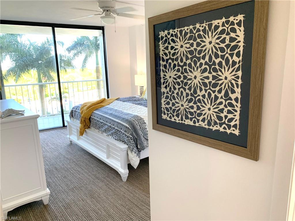 Bedroom with access to outside, carpet flooring, a wall of windows, and a ceiling fan