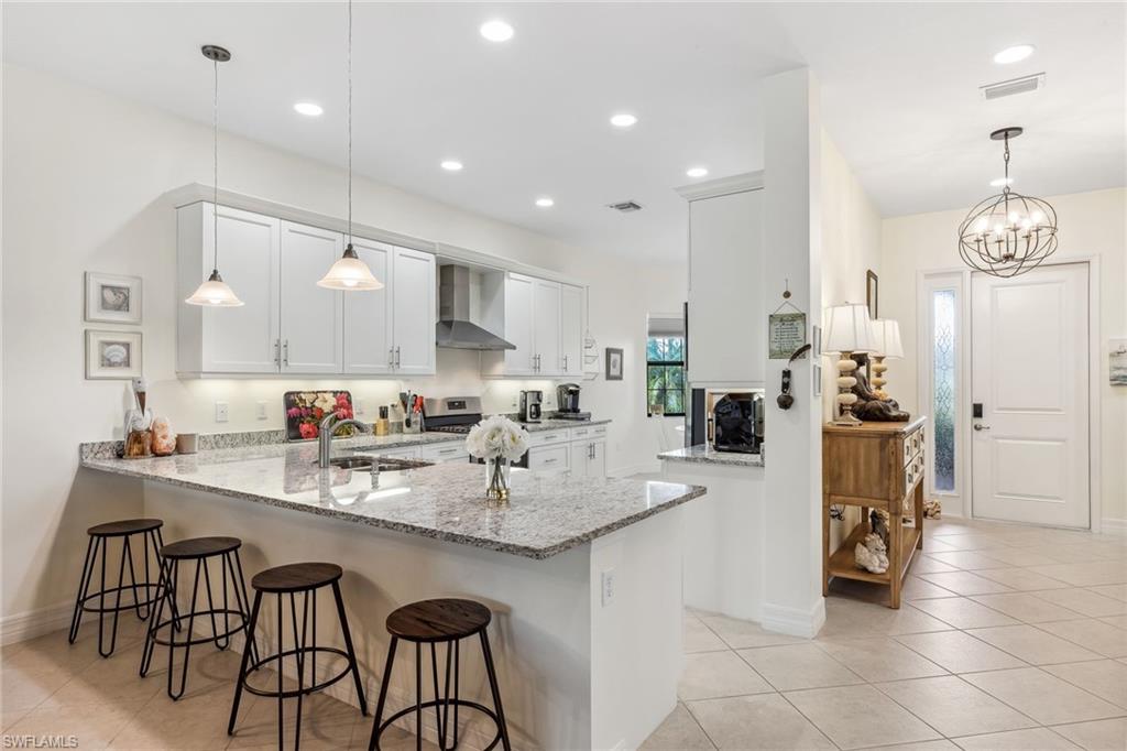 Kitchen features stainless steel appliances, vented hood.