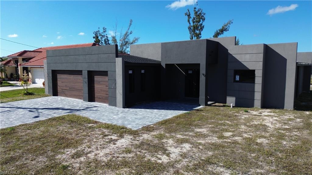 Contemporary home featuring stucco siding, an attached garage, and decorative driveway