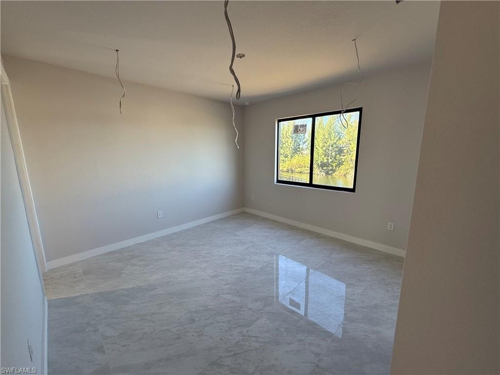Empty room featuring light marble finish flooring and baseboards