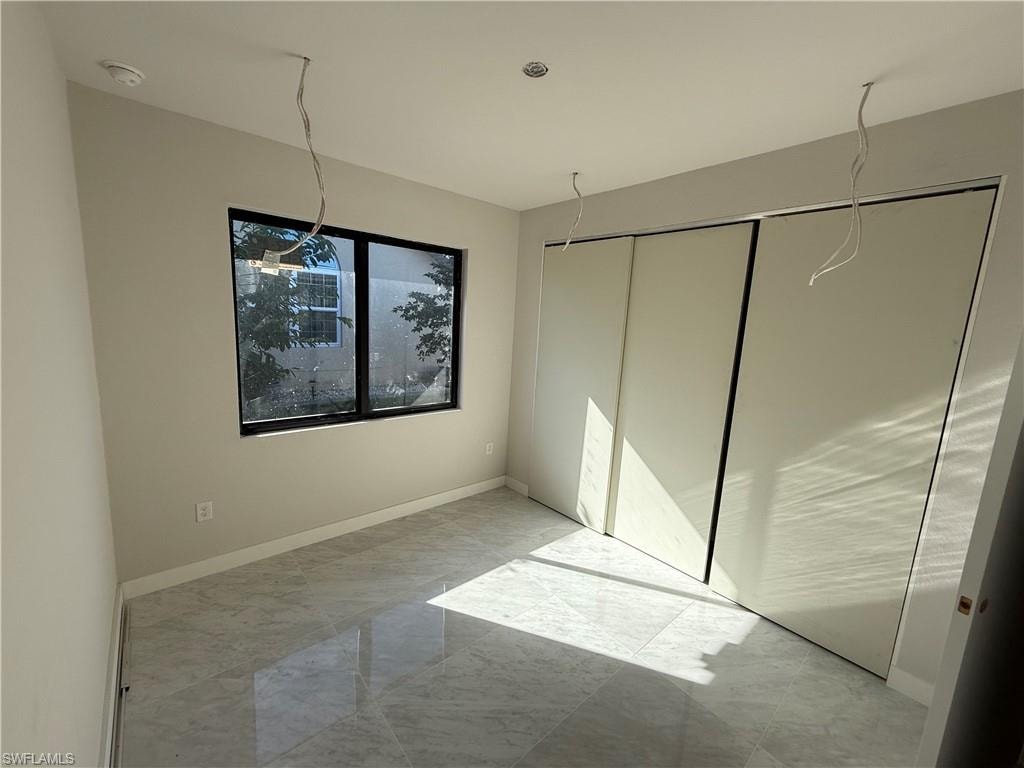 Unfurnished bedroom with light marble finish floors and baseboards
