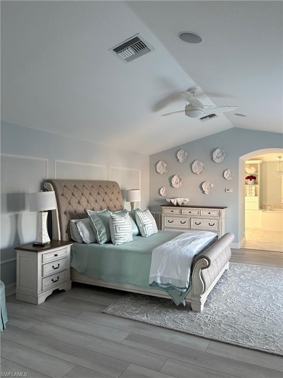 Bedroom featuring arched walkways, light wood-style floors, a ceiling fan, and lofted ceiling