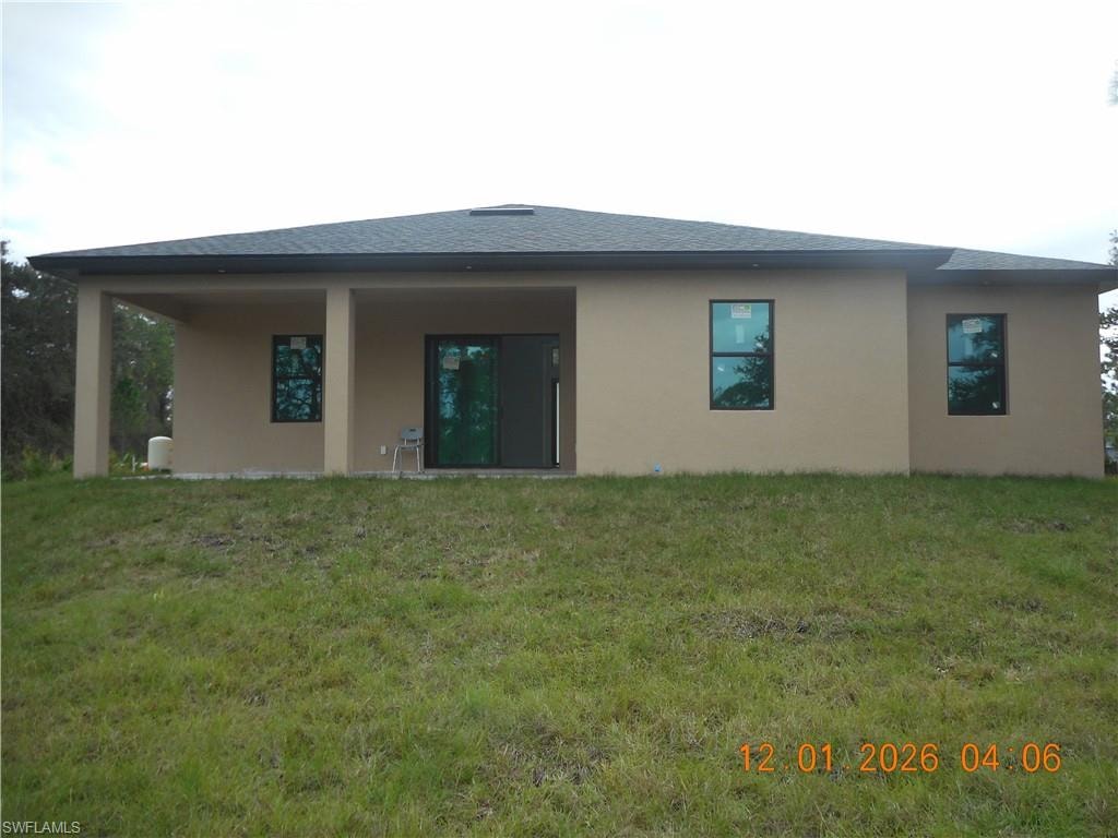 Back of property featuring stucco siding, a yard, a patio area, and roof with shingles