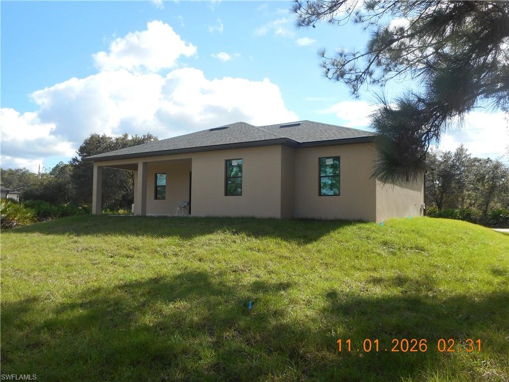 Back of property with stucco siding, a yard, and a patio
