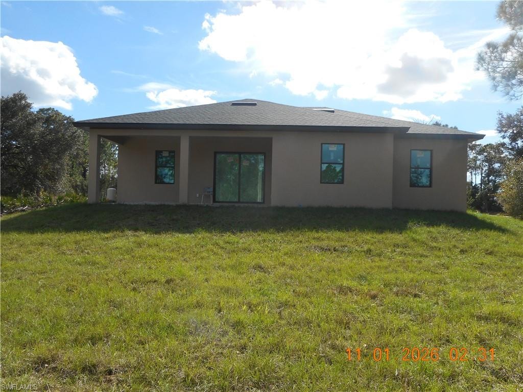 Back of property with a yard, stucco siding, and a patio