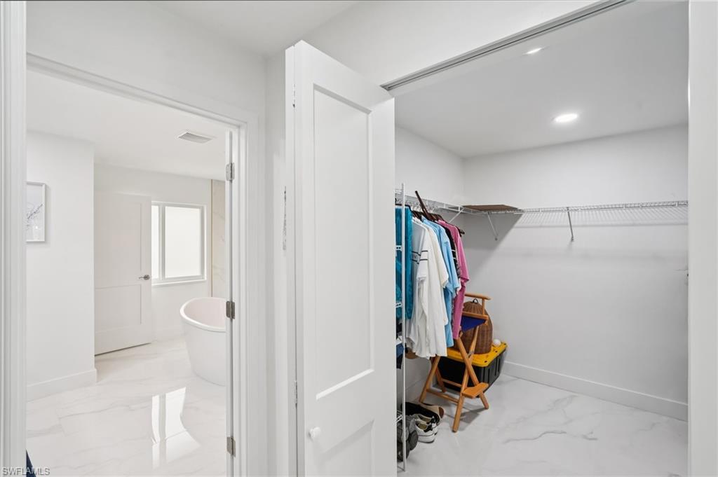 Walk in closet with light marble finish flooring