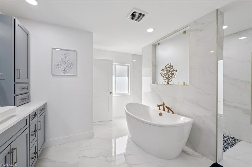 Full bathroom featuring light marble finish flooring, vanity, a marble finish shower, recessed lighting, and a soaking tub