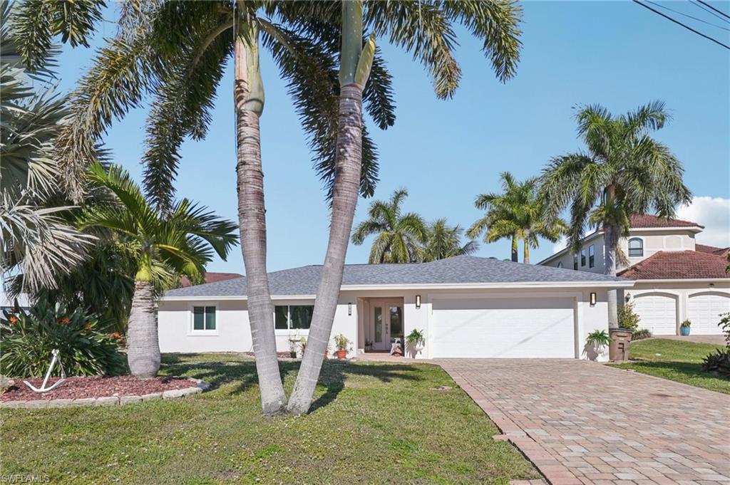 View of front of house featuring stucco siding, a front lawn, and decorative driveway