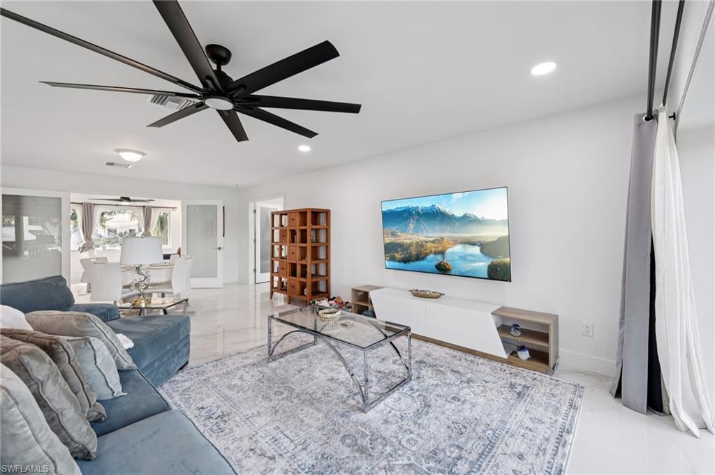Living room with recessed lighting, ceiling fan, and light marble finish flooring