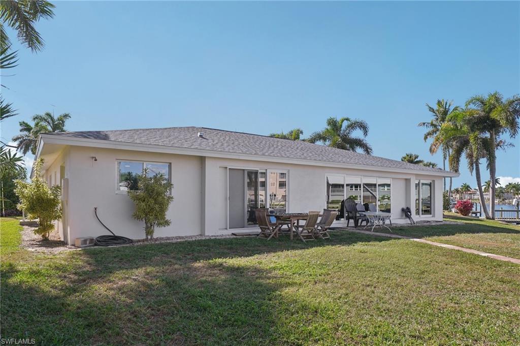 Rear view of property with a lawn, a patio, and stucco siding