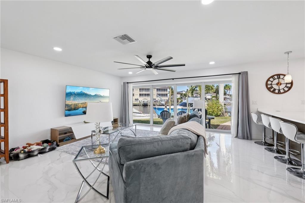 Living room with light marble finish floors, a ceiling fan, and recessed lighting
