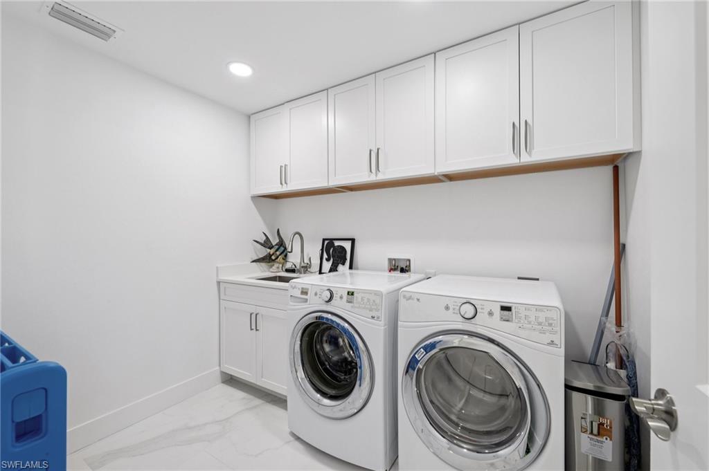 Washroom featuring light marble finish floors, separate washer and dryer, cabinet space, and recessed lighting