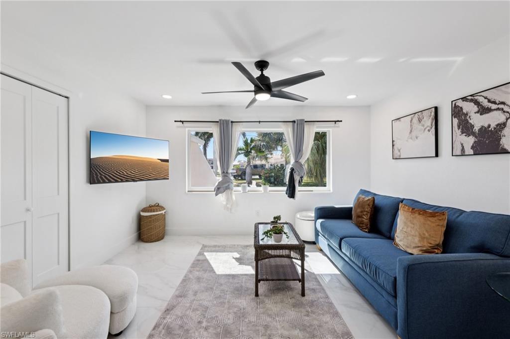 Living room with marble look tiles, ceiling fan, and recessed lighting