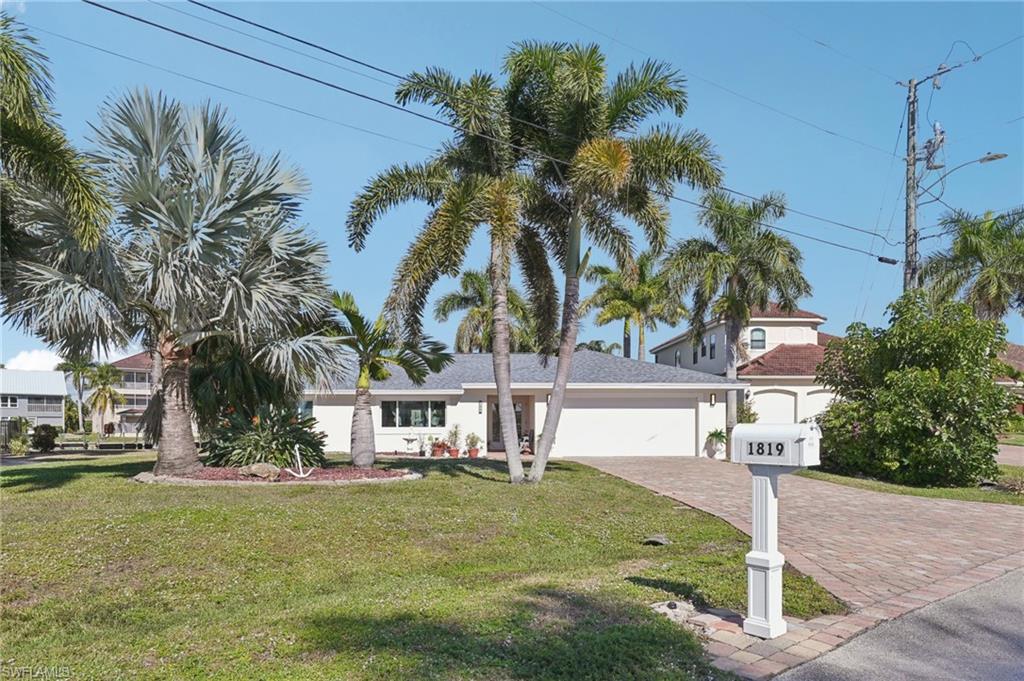 View of front of home featuring a garage, a front yard, decorative driveway, and stucco siding