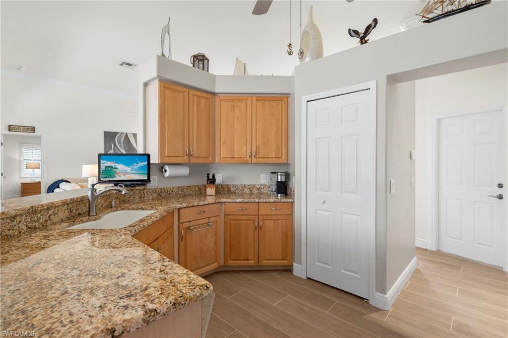 Kitchen featuring sink, ceiling fan, kitchen peninsula, and light stone countertops