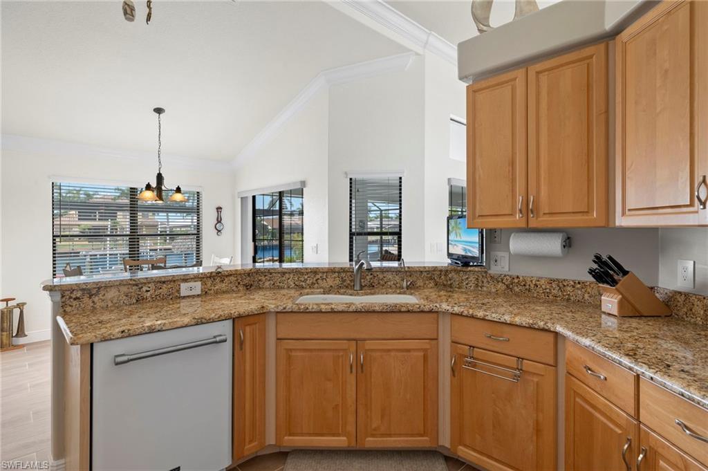 Kitchen featuring a healthy amount of sunlight, sink, hanging light fixtures, kitchen peninsula, and light stone counters