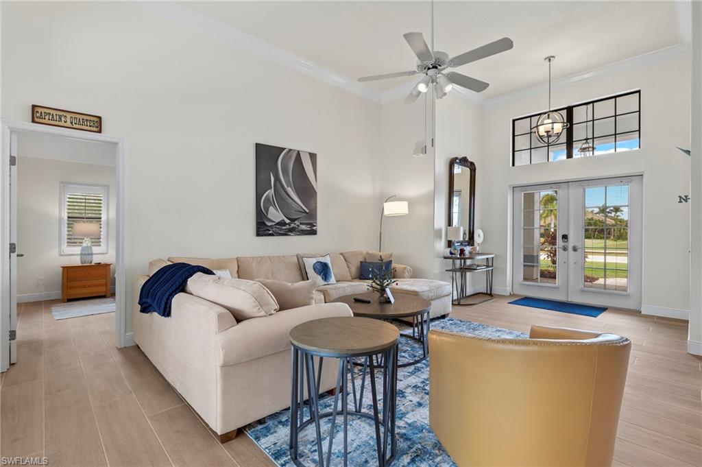 Living room featuring ceiling fan, french doors, a high ceiling, and ornamental molding
