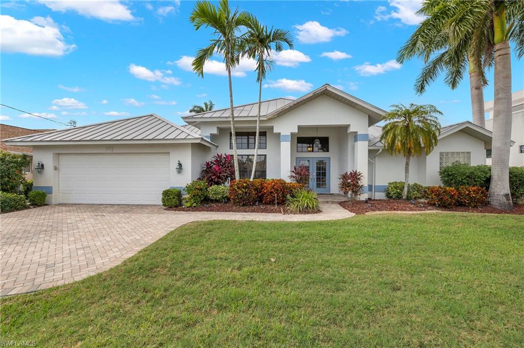 Ranch-style home with a garage, a front lawn, and french doors