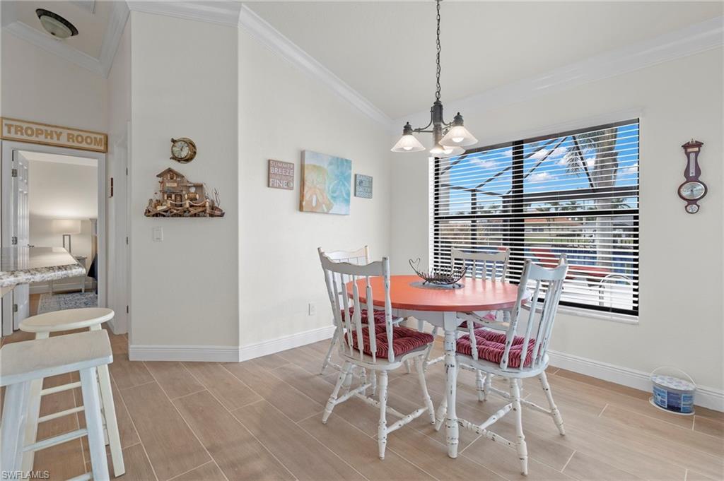 Dining room with lofted ceiling, crown molding, and an inviting chandelier