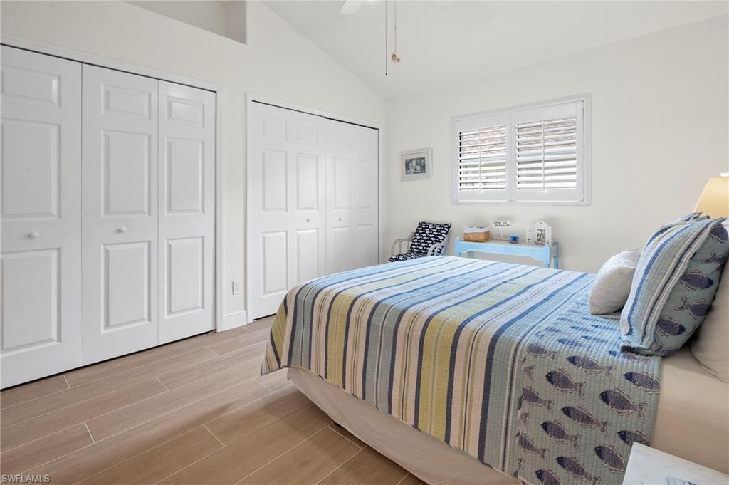 Bedroom featuring light wood-type flooring, vaulted ceiling, two closets, and ceiling fan