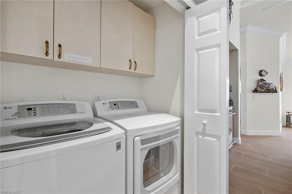 Laundry area featuring washer and dryer, cabinets, and light wood-type flooring