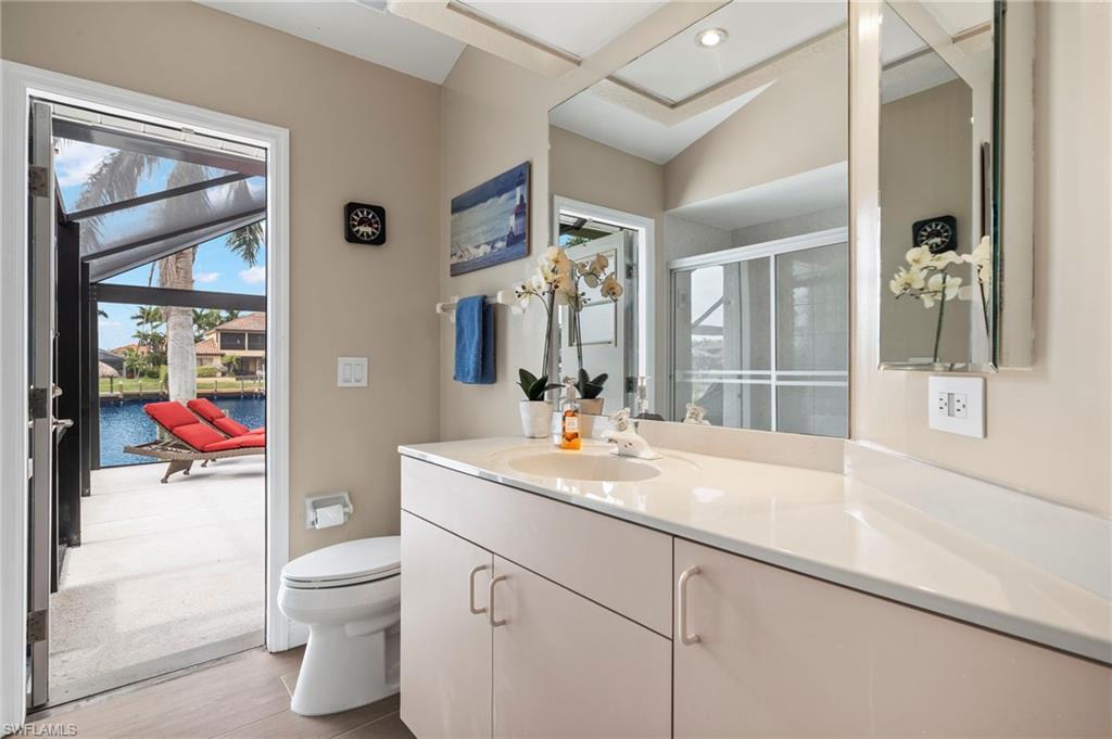 Bathroom featuring hardwood / wood-style flooring, a water view, toilet, walk in shower, and vanity