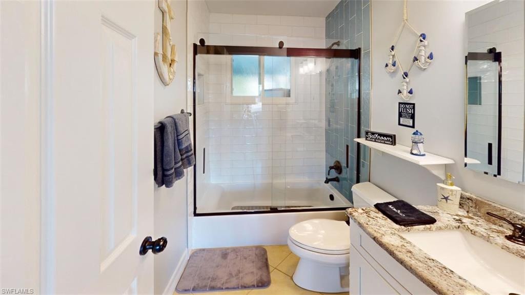 Bathroom with vanity, combined bath / shower with glass door, and light tile patterned floors
