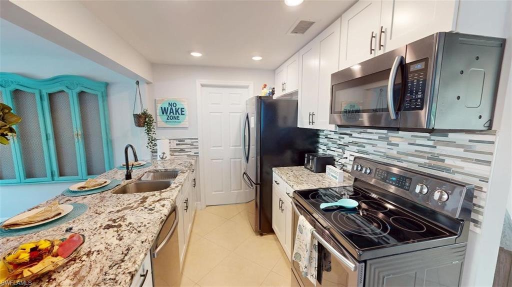 Kitchen featuring stainless steel appliances, light stone countertops, white cabinets, recessed lighting, and light tile patterned floors