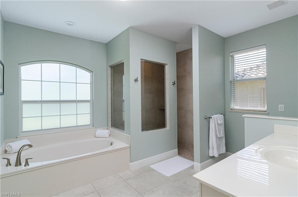 Bathroom featuring vanity, tile patterned floors, and separate shower and tub