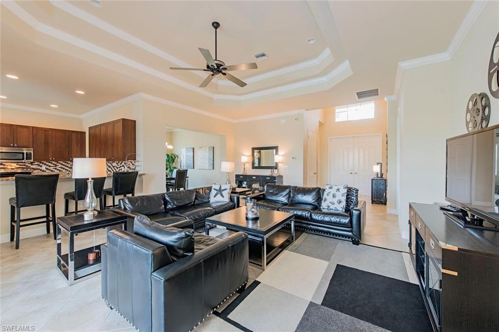 Living area with crown molding, ceiling fan, and a raised ceiling