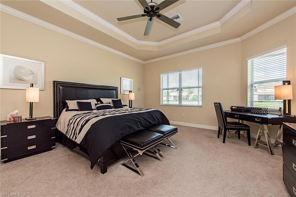 Bedroom with light carpet, ornamental molding, a raised ceiling, and a ceiling fan