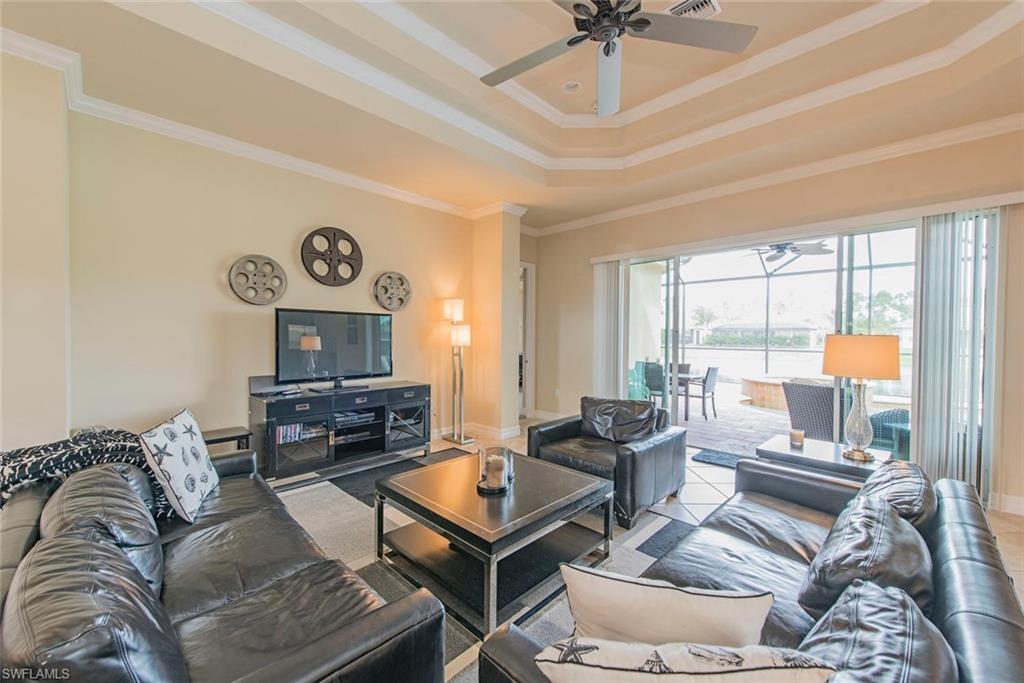 Tiled living room with a sunroom, ornamental molding, a raised ceiling, and ceiling fan