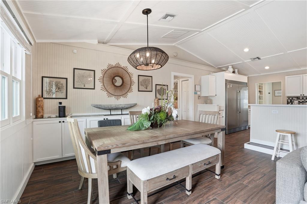 Dining space with vaulted ceiling, a chandelier, and dark wood-style floors - Virtually Edited Image